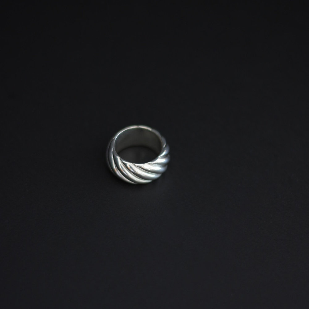 A silver twisted ring with a textured spiral design, shown on a solid black background.