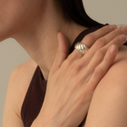 A close-up lifestyle shot of a model wearing a wide, textured silver ring on her finger, resting her hand on her shoulder.