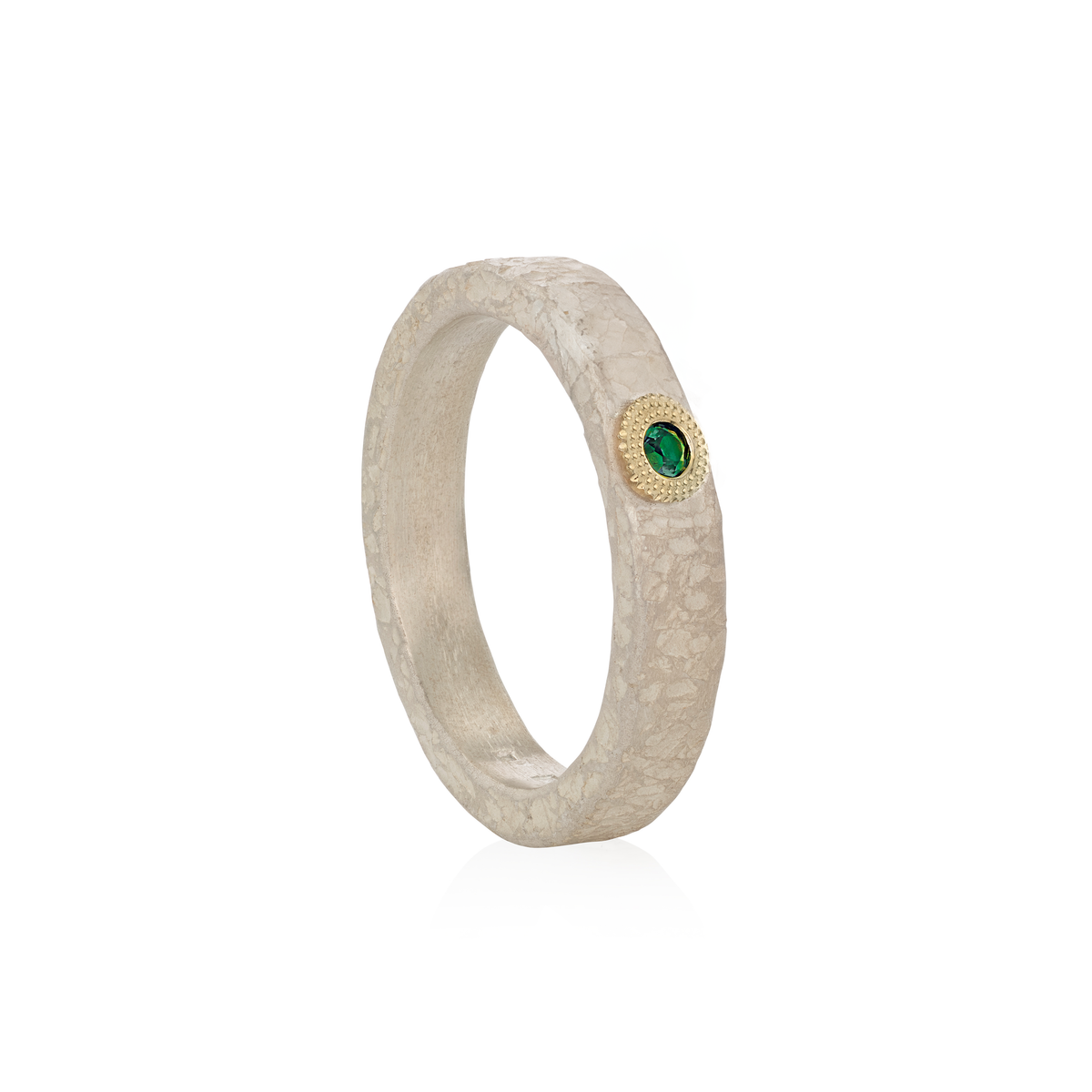 A textured silver ring with a small round green emerald gemstone surrounded by a gold halo, shown on a clean white background.