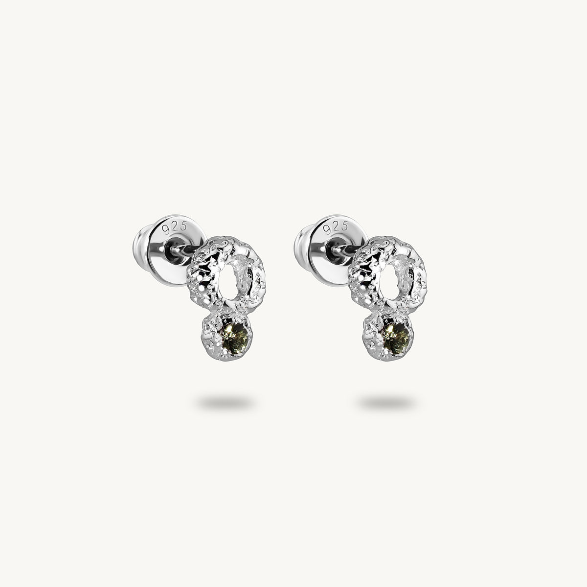 A pair of silver stud earrings with textured circular clusters and small oval green sapphires drops, shown on a light cream background.