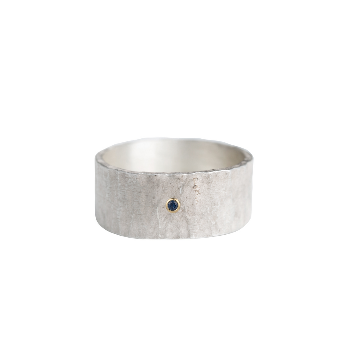 A wide sterling silver band with a hammered surface set with a blue diamond. 