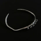 One-of-a-kind silver bangle featuring an organic, asymmetrical shape with delicate dangling accents for a modern, minimalist edge.