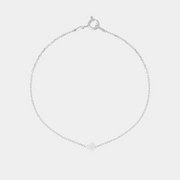 Silver bracelet with heart-shaped pendant on a light gray background