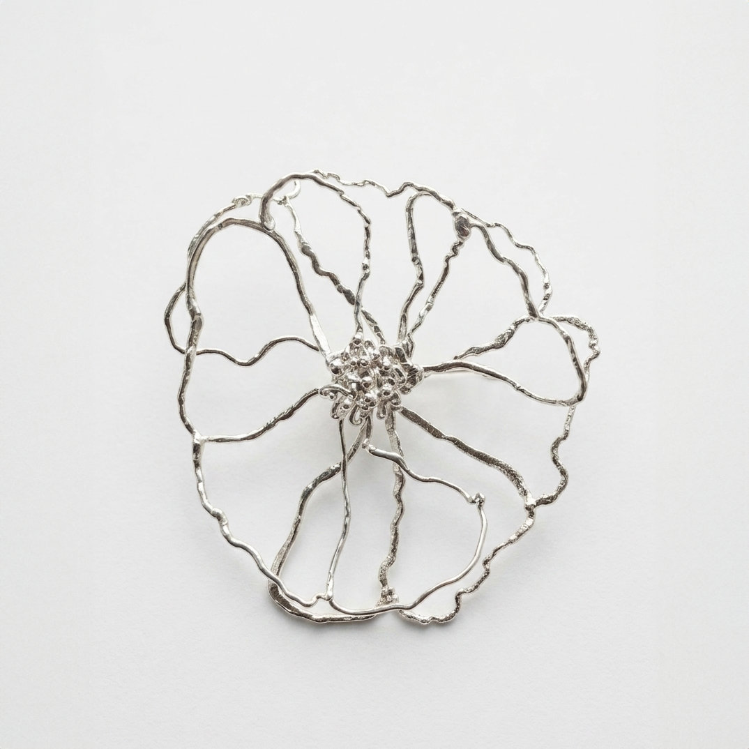 Silver flower-shaped brooch on a light gray background