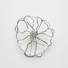 Silver flower-shaped brooch on a light gray background