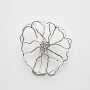 Silver flower-shaped brooch on a light gray background