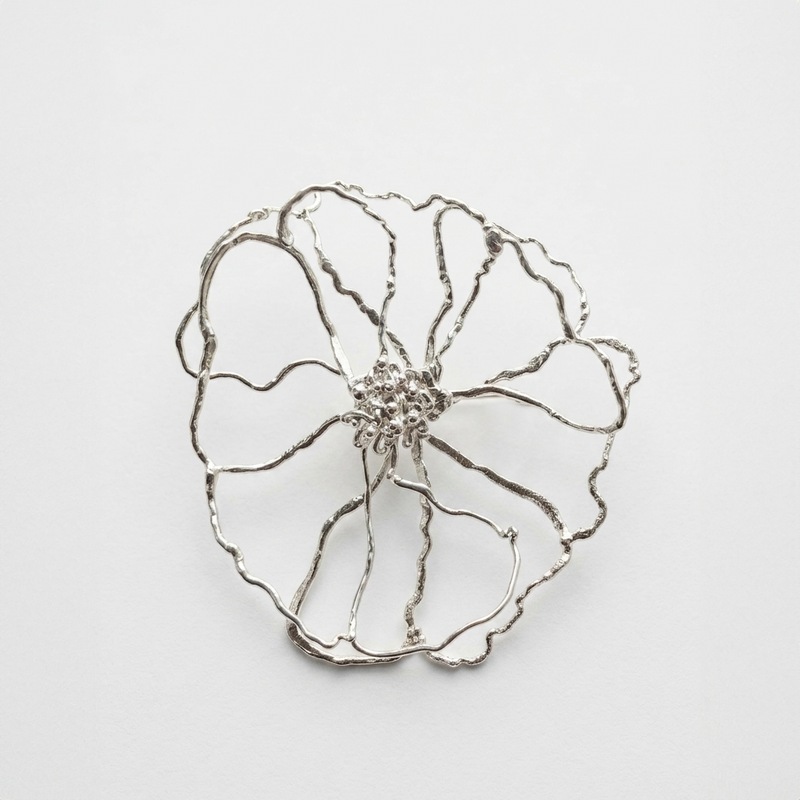 Silver flower-shaped brooch on a light gray background