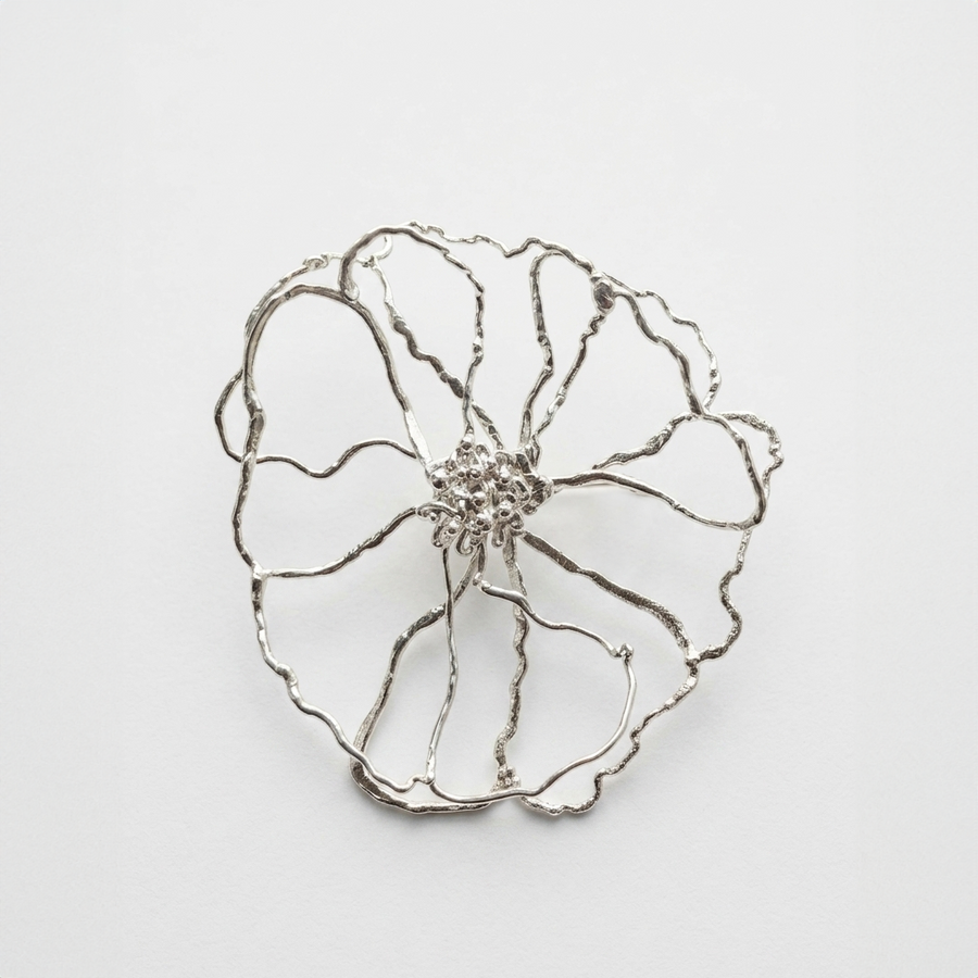 Silver flower-shaped brooch on a light gray background