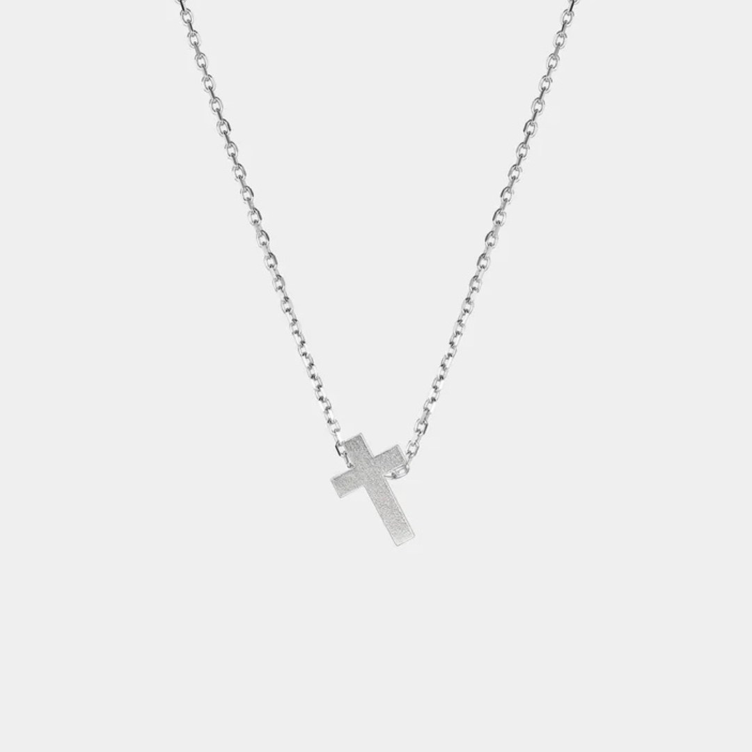 Silver cross necklace on a light gray background