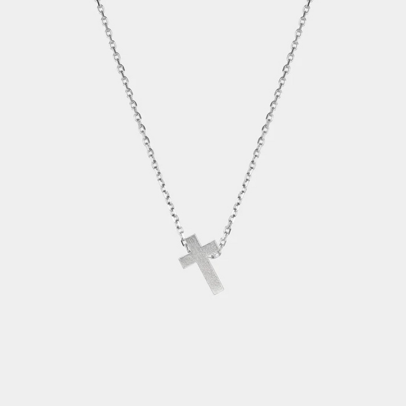 Silver cross necklace on a light gray background