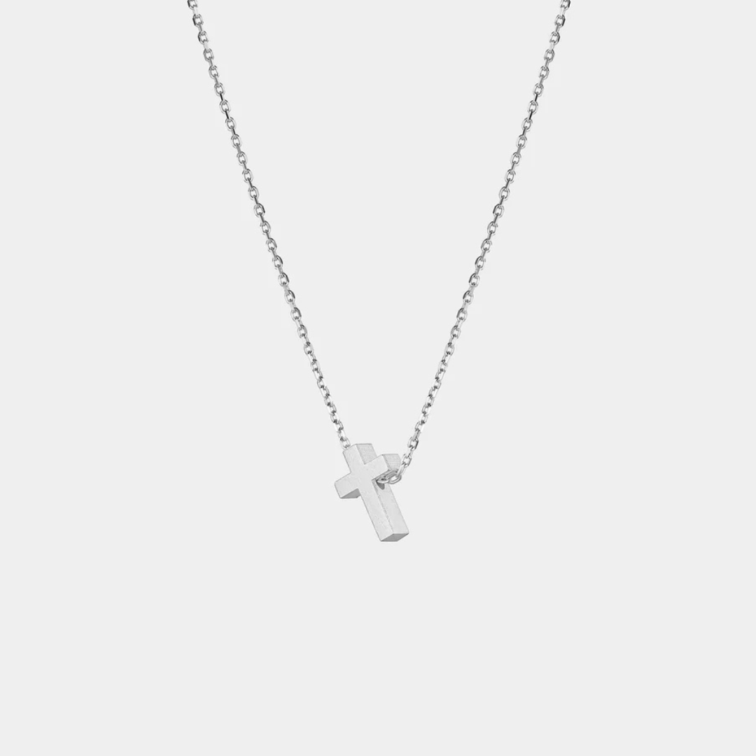 Silver cross necklace on a light gray background