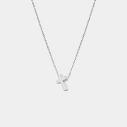 Silver cross necklace on a light gray background