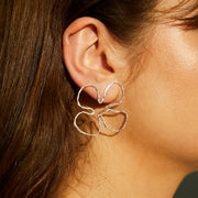 Silver earrings shaped in an organic, flowing silhouette.