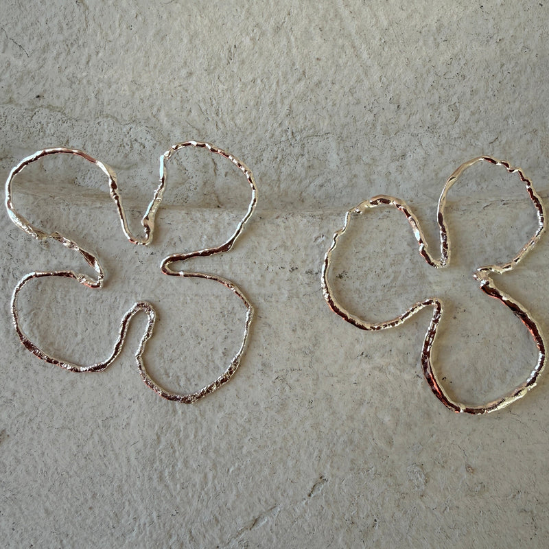 Silver earrings shaped in an organic, flowing silhouette.