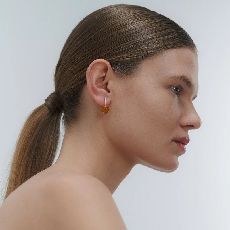Silver earrings, featuring a structured band and a bold amber element.
