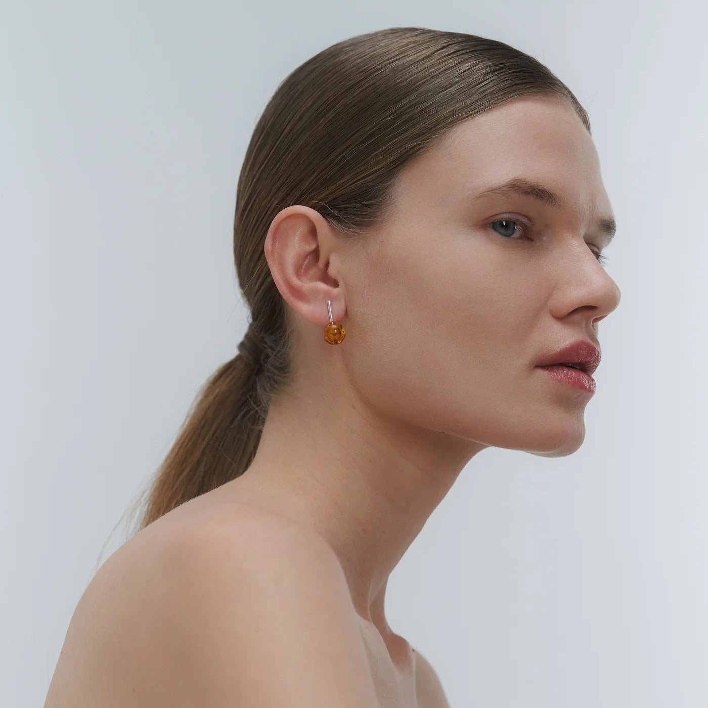 Silver earrings, featuring a structured band and a bold amber element.
