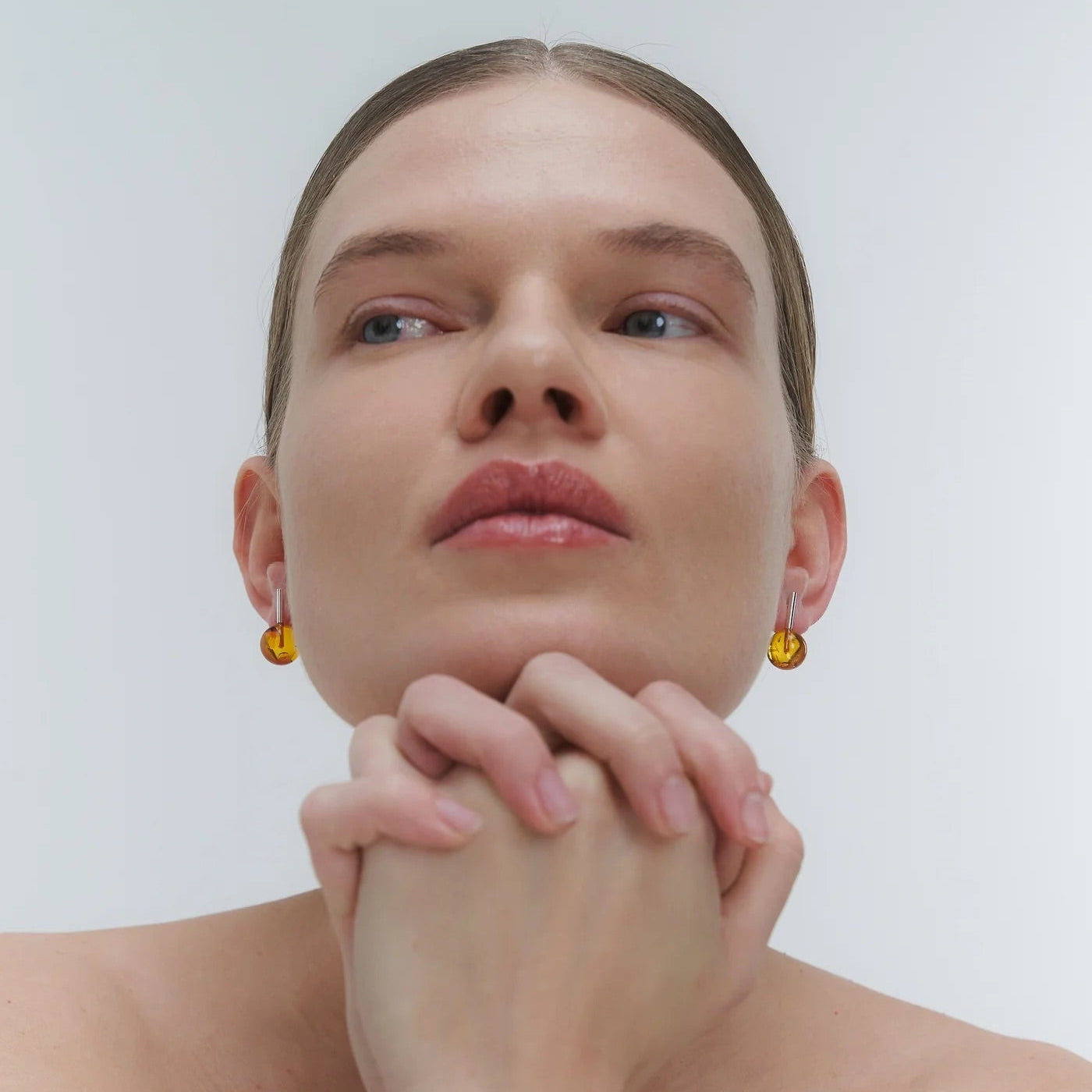 Silver earrings, featuring a structured band and a bold amber element.