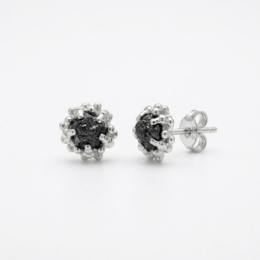 Pair of silver earrings with black diamonds on a white background