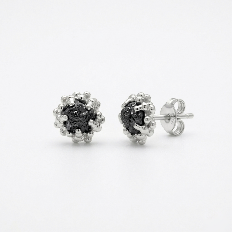 Pair of silver earrings with black diamonds on a white background