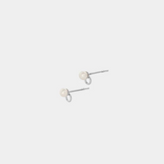A pair of silver earrings featuring a round pearl connected by a silver dot, presented on a white background.