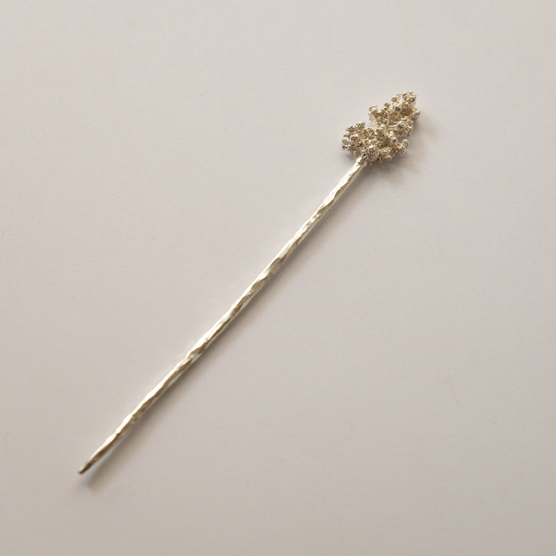 Silver hairpin with decorative top on a light gray background