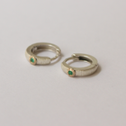 Pair of silver hoop earrings with emeralds on a light gray background