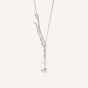 A silver necklace with a heart-shaped pendant and an organic hook fastening.