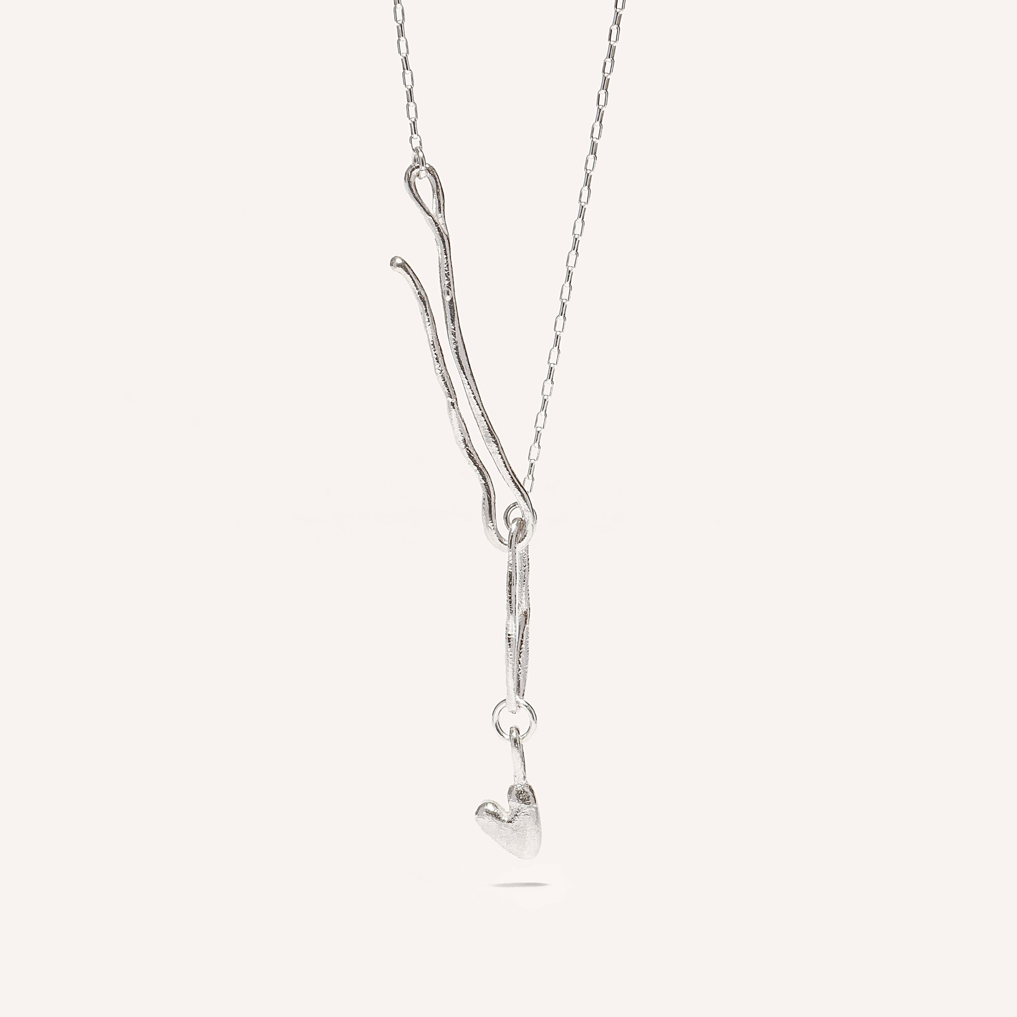 A silver necklace with a heart-shaped pendant and an organic hook fastening.