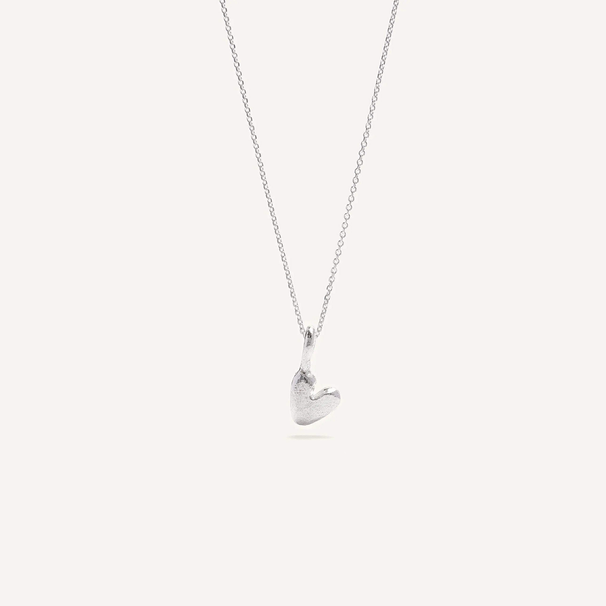 A heart-shaped silver necklace with a pendant on a chain, displayed against a white background.