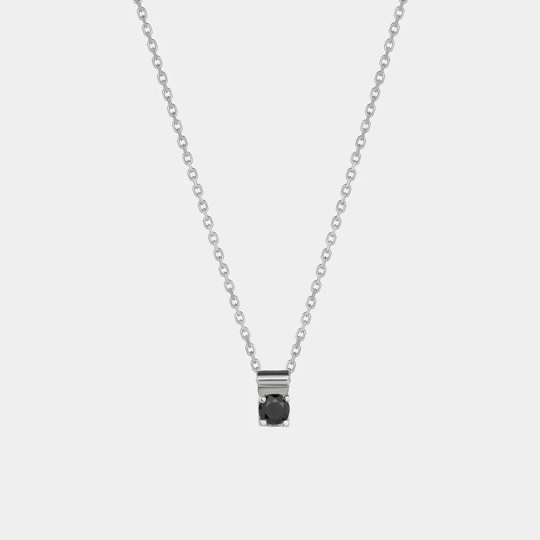A silver necklace with a black zirconium pendant, designed to resemble a star, hanging on a chain.