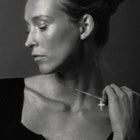 Black and white close-up of a woman adjusting a necklace with a cross pendant.