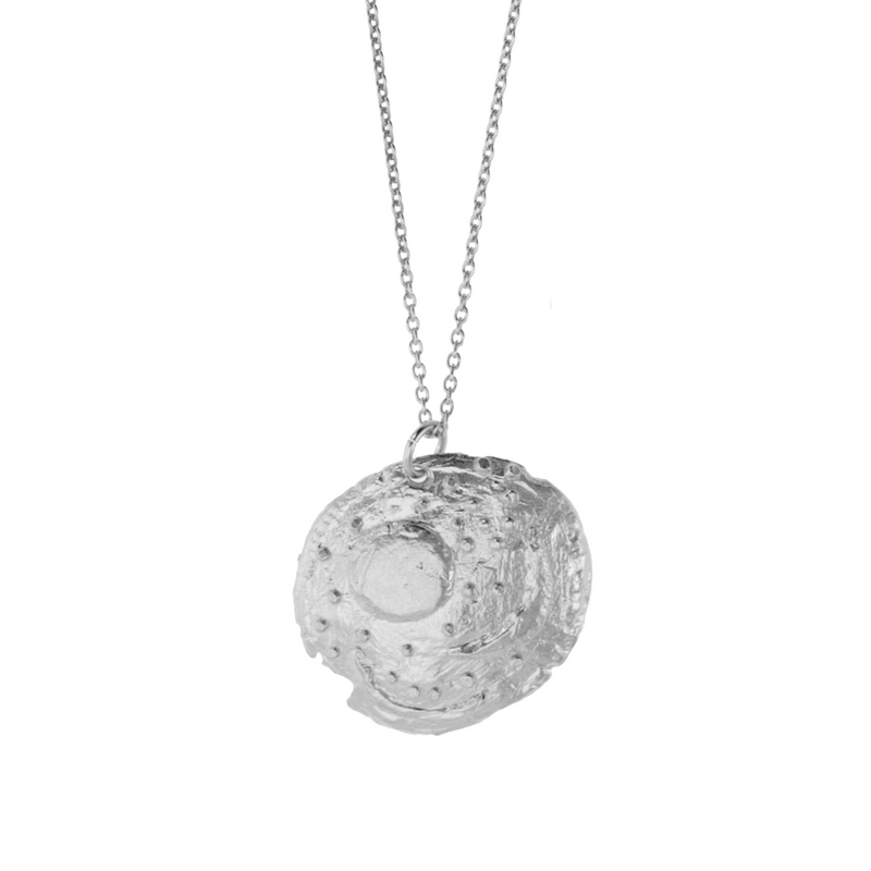 Silver pendant featuring symbols representing the Sun, the full moon, a crescent moon, and stars, including the Pleiades. 