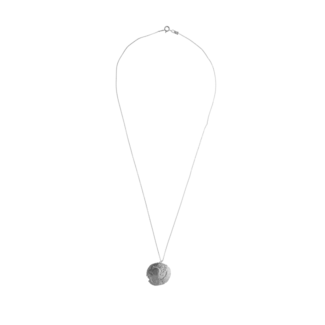 Silver pendant featuring symbols representing the Sun, the full moon, a crescent moon, and stars, including the Pleiades. 