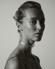 Black and white portrait of a woman wearing a delicate necklace against a plain background
