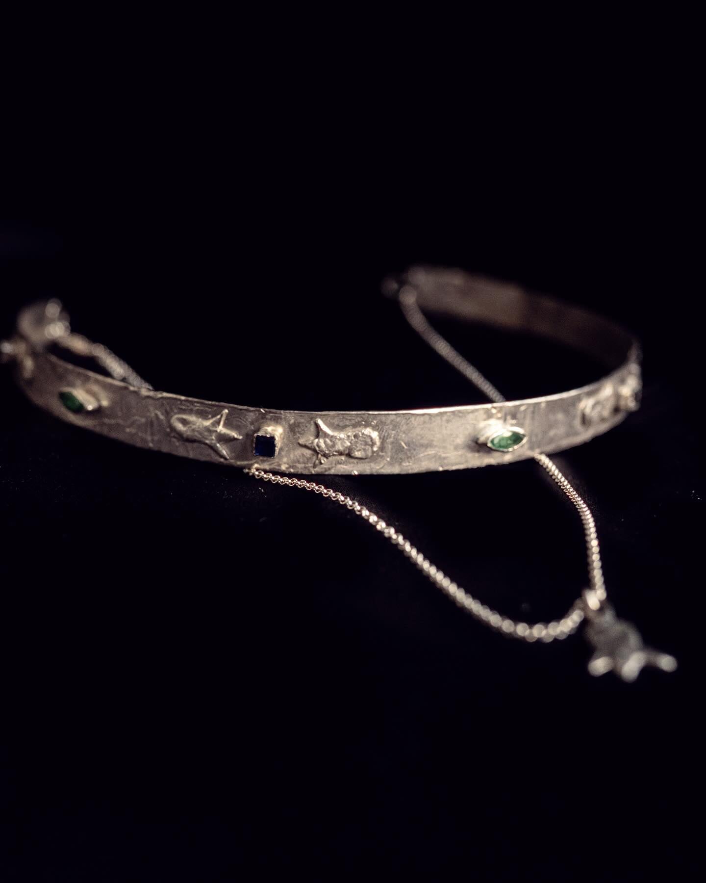Silver choker necklace with engraved details on a black background