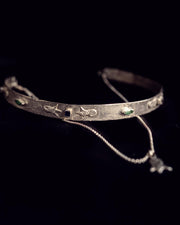 Silver choker necklace with engraved details on a black background