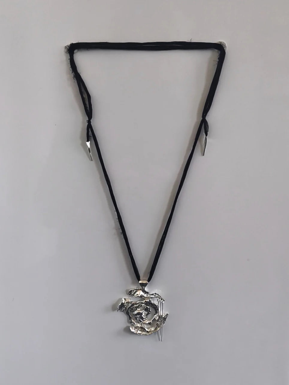 One-of-a-kind necklace featuring a unique water-cast sterling silver pendant with an organic, sculptural form and delicate linear drops. 