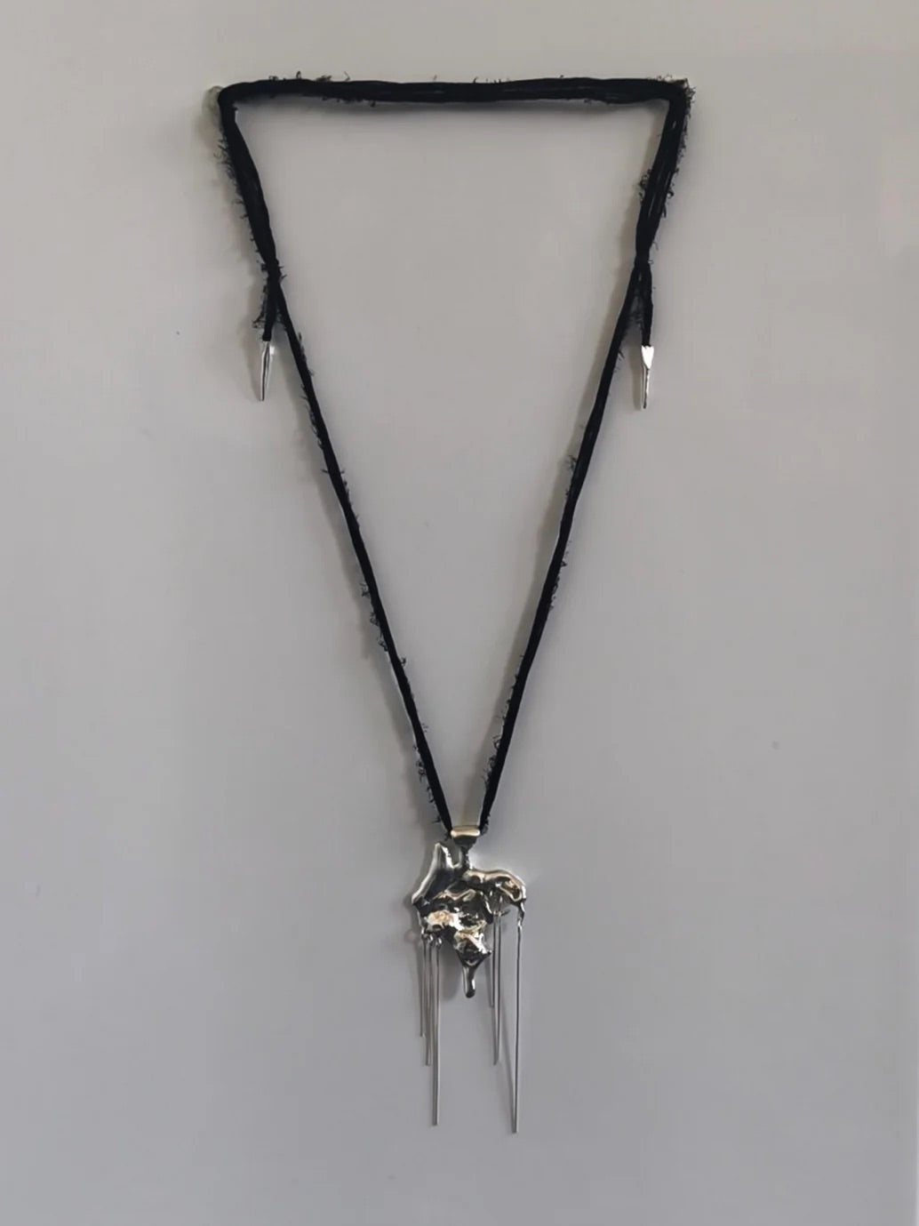 One-of-a-kind necklace featuring a unique water-cast sterling silver pendant with an organic, sculptural form and delicate linear drops.