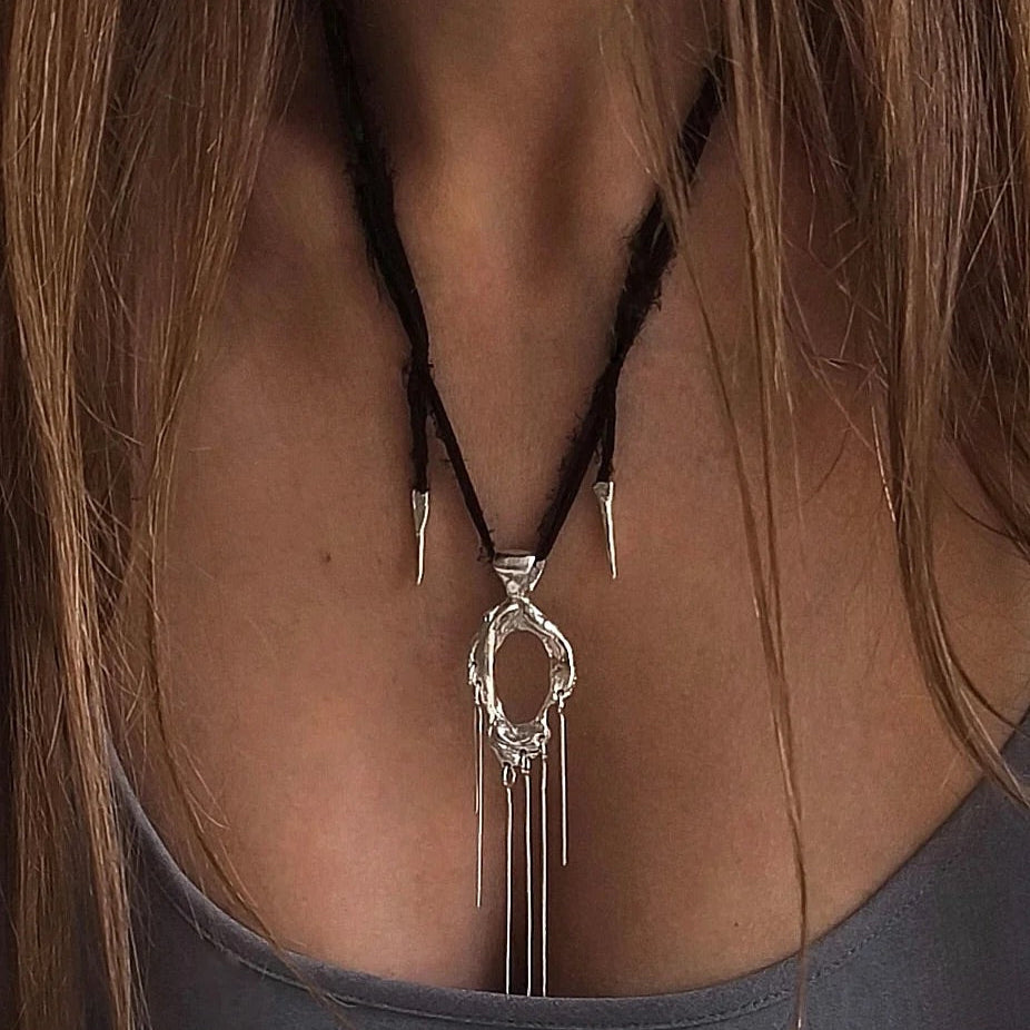 One-of-a-kind necklace featuring a unique water-cast sterling silver pendant with an organic, sculptural form and delicate linear drops. 