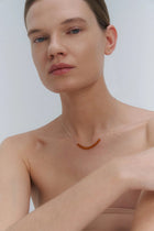 Woman wearing a silver necklace with Baltic amber beads against a plain background