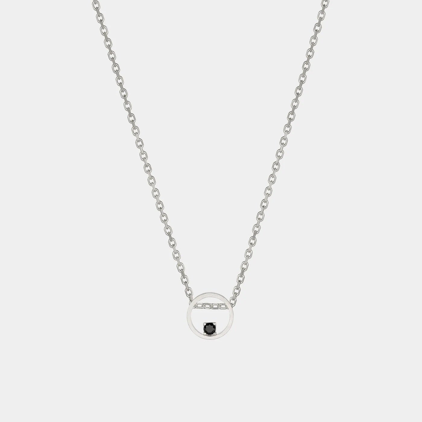 Silver necklace with a small round pendant on a light gray background