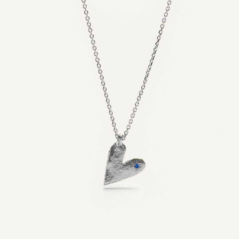 Silver heart-shaped pendant necklace with a blue sapphire on a white background