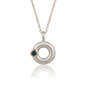 Silver necklace with a circular pendant featuring a blue sapphire on a white background