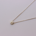 Delicate necklace with a small diamond pendant on a light gray background