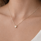 Gold necklace with a small round pendant on a person's neck
