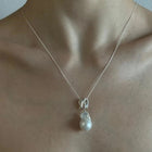 Infinity-shaped pendant featuring baroque shaped freshwater pearl. 