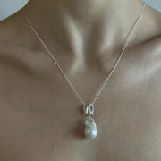 Infinity-shaped pendant featuring baroque shaped freshwater pearl. 