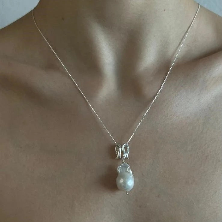 Infinity-shaped pendant featuring baroque shaped freshwater pearl. 