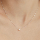 A silver necklace featuring a single pearl diverged from a chain, displayed against a neutral background.
