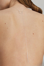 Thin silver necklace on a person's neck and back.